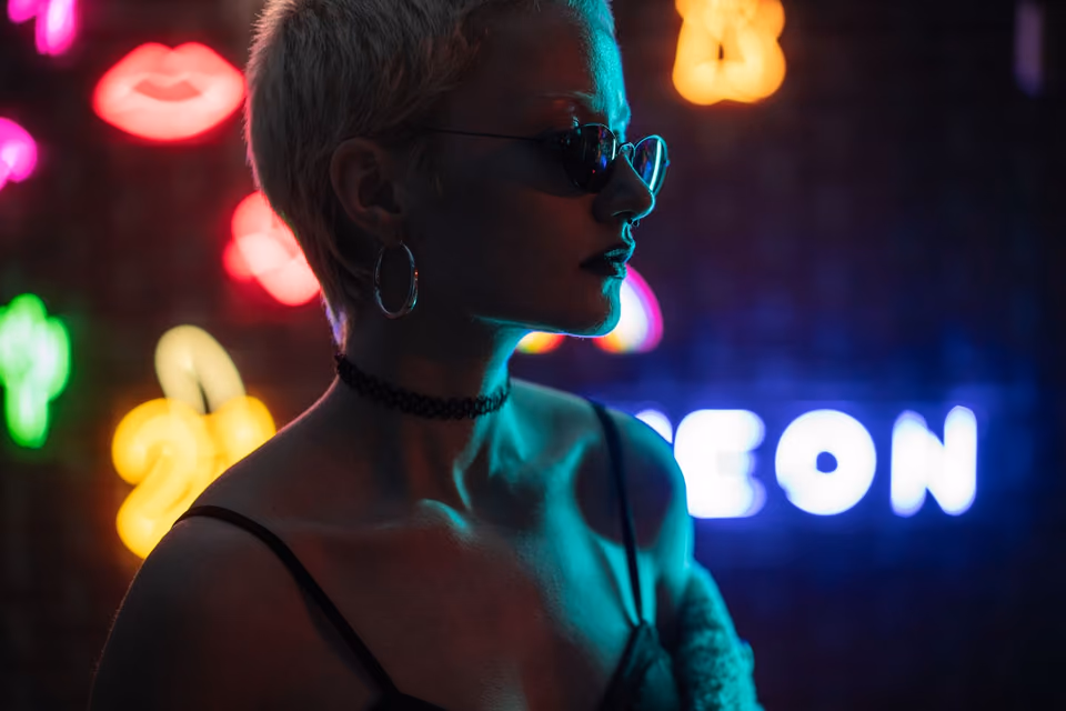 A woman in sunglasses between neon letters